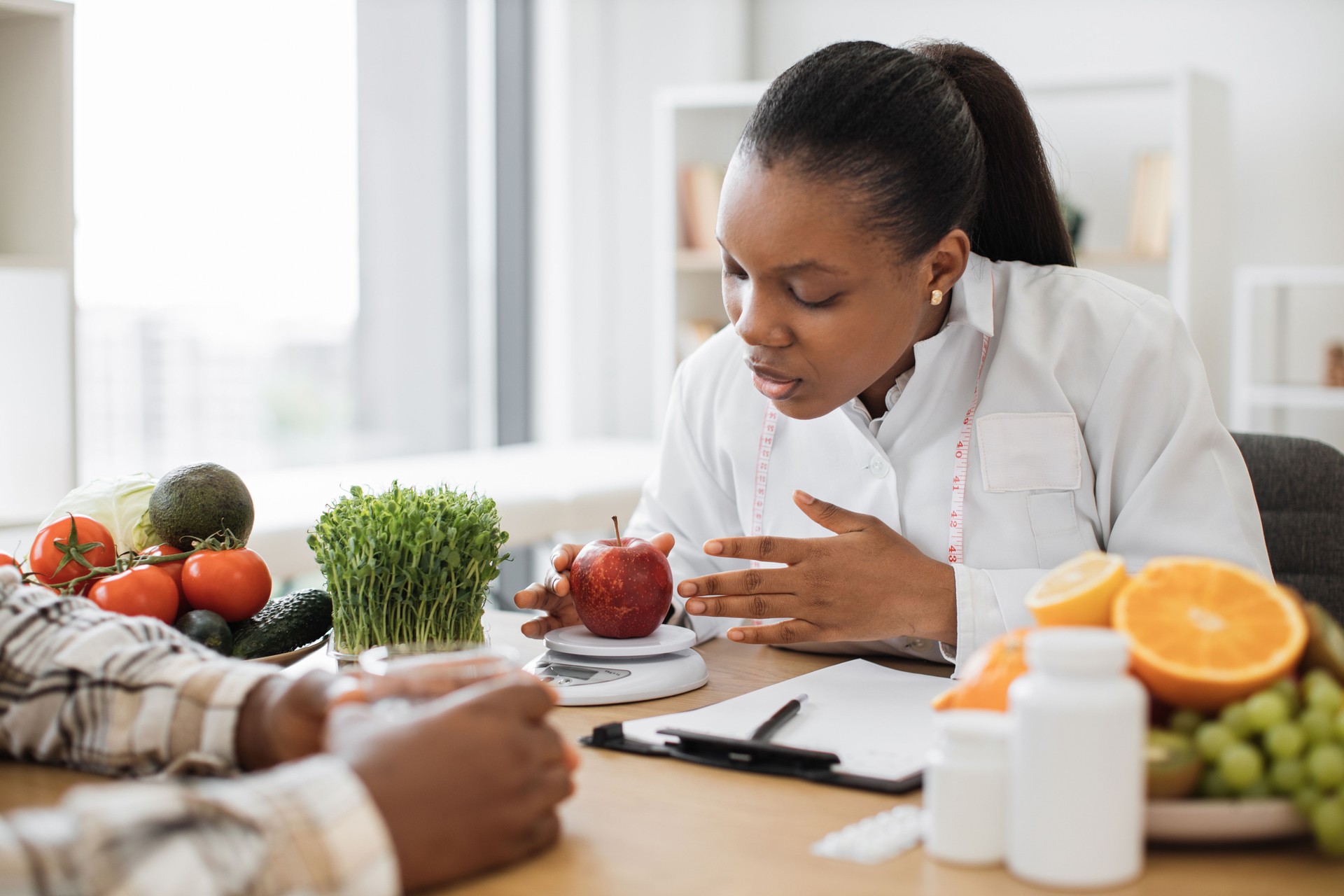 Nutritionist weighing apple on digital scale in hospital